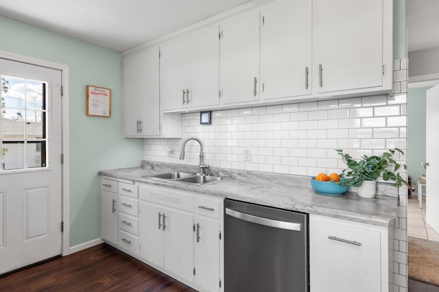 kitchen with stainless steel dishwasher, light countertops, backsplash, a sink, and white cabinetry