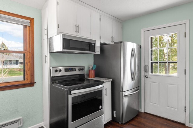 kitchen with baseboard heating, light countertops, white cabinets, appliances with stainless steel finishes, and dark wood finished floors