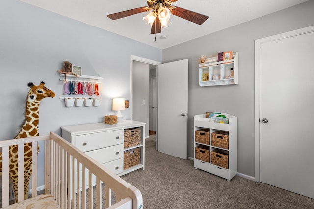 carpeted bedroom featuring a crib and ceiling fan