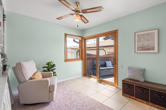 living area featuring baseboards, ceiling fan, and light tile patterned flooring