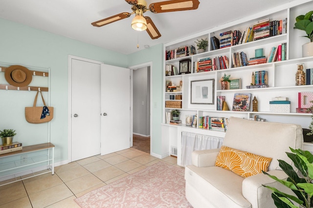 living area featuring baseboards, a ceiling fan, and tile patterned flooring