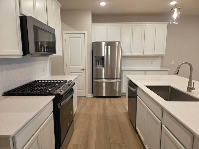 kitchen with light wood finished floors, white cabinets, stainless steel appliances, and a sink