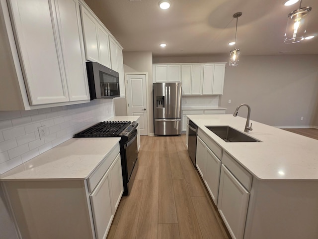 kitchen with pendant lighting, light wood-style flooring, a sink, tasteful backsplash, and stainless steel appliances