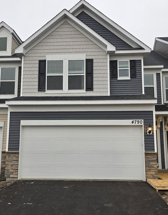 view of front of home featuring stone siding, driveway, and a garage