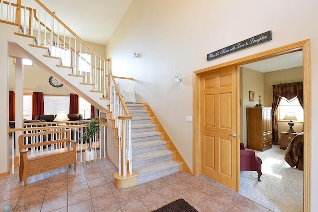 stairway featuring a high ceiling, carpet flooring, and tile patterned flooring