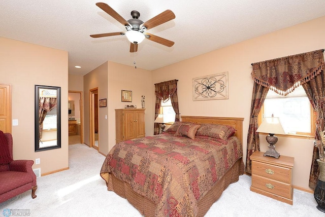 bedroom with a textured ceiling, connected bathroom, baseboards, light colored carpet, and ceiling fan