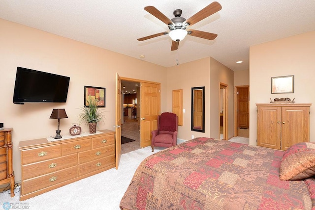 bedroom featuring light carpet, a textured ceiling, and a ceiling fan