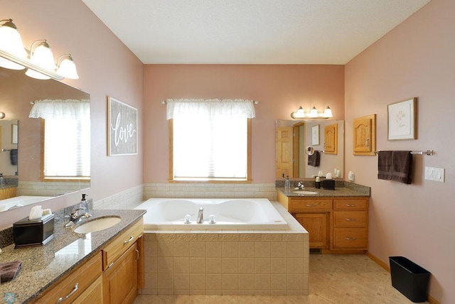 full bath featuring two vanities, a garden tub, and a sink