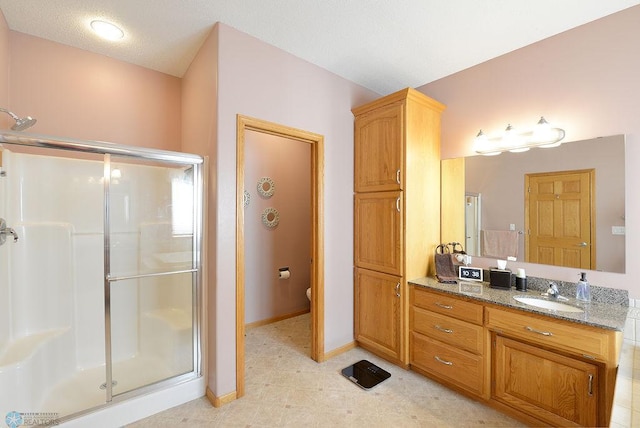 full bath with a shower stall, toilet, vanity, and baseboards