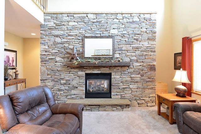 living room with plenty of natural light, a stone fireplace, a towering ceiling, and carpet flooring