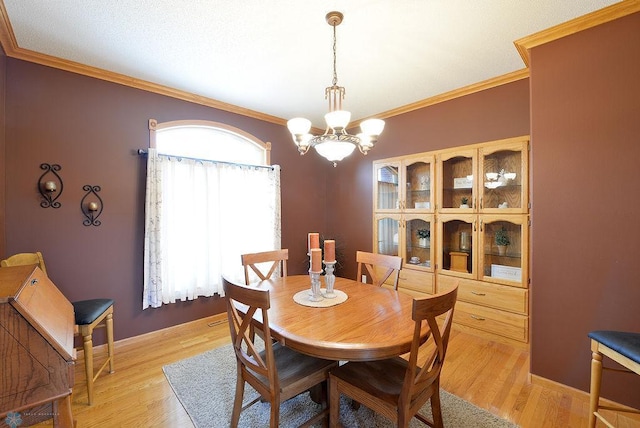 dining room featuring a chandelier, light wood-style flooring, and crown molding