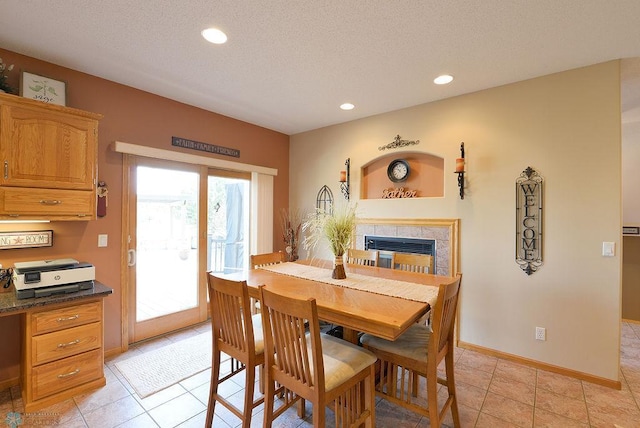 dining area with a textured ceiling, recessed lighting, light tile patterned floors, baseboards, and a tile fireplace