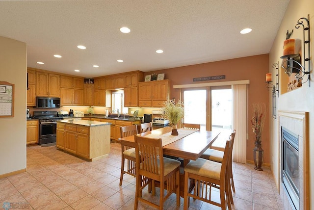 kitchen with stainless steel range with gas stovetop, a kitchen island, black microwave, and a healthy amount of sunlight