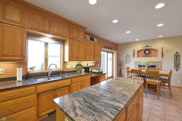 kitchen featuring plenty of natural light, a center island, dark stone counters, and a sink