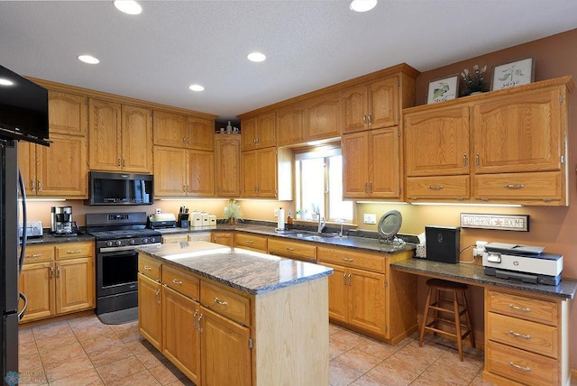 kitchen featuring dark stone countertops, gas stove, a kitchen island, recessed lighting, and a sink