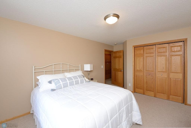 bedroom with carpet flooring, baseboards, a closet, and a textured ceiling