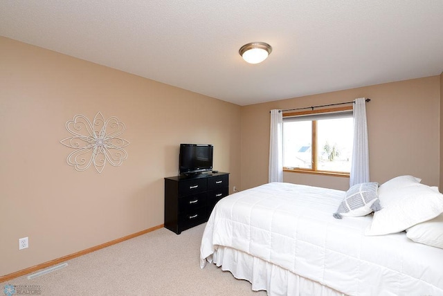 bedroom with visible vents, light colored carpet, and baseboards