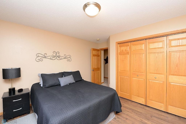 bedroom featuring light wood-style floors, a closet, and a textured ceiling