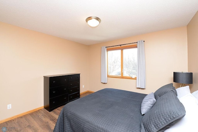 bedroom featuring a textured ceiling, baseboards, and wood finished floors