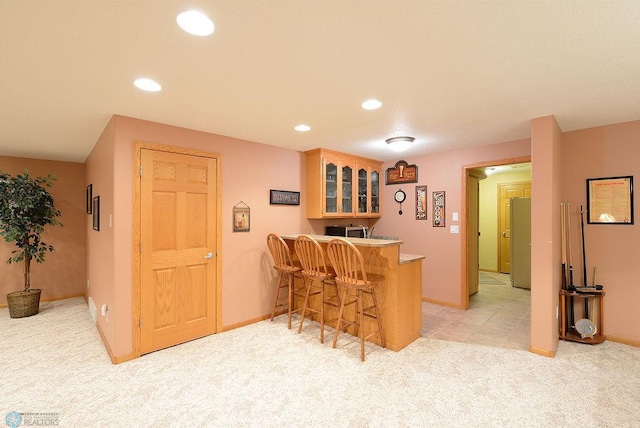 kitchen featuring recessed lighting, light colored carpet, a peninsula, and freestanding refrigerator