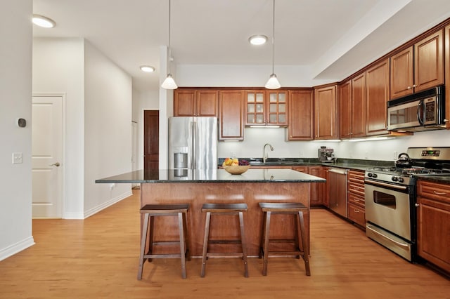 kitchen featuring a breakfast bar area, light wood-style flooring, appliances with stainless steel finishes, and a sink