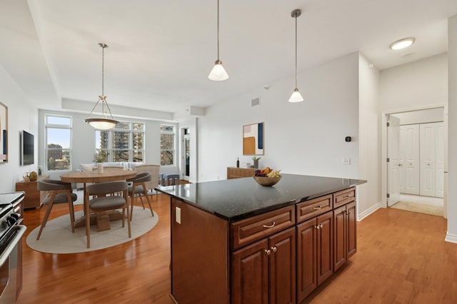 kitchen featuring gas stove, visible vents, a kitchen island, light wood-style flooring, and pendant lighting