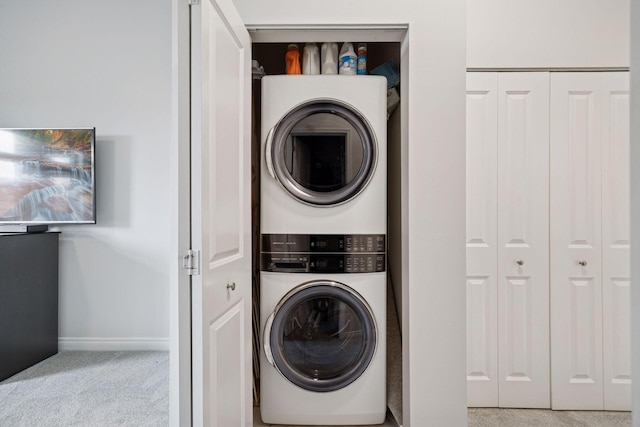 clothes washing area featuring carpet flooring, laundry area, stacked washer / drying machine, and baseboards