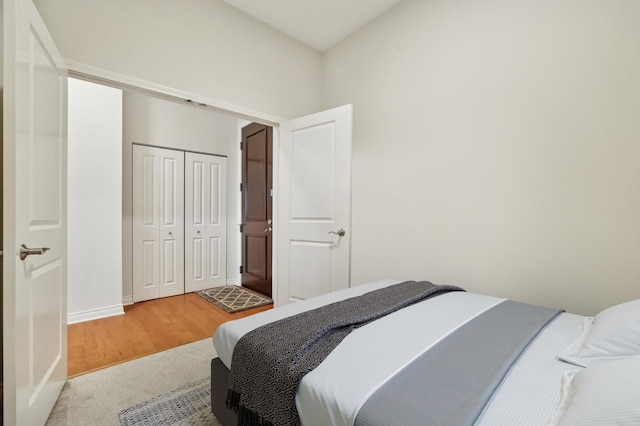 bedroom featuring a closet, light wood finished floors, and light carpet