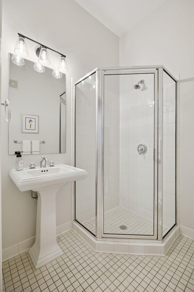 bathroom with tile patterned floors, a sink, a stall shower, and vaulted ceiling