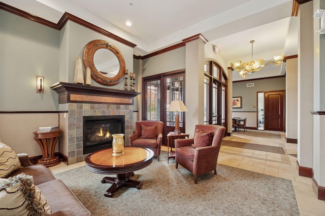 living room with a tiled fireplace, baseboards, a chandelier, and ornamental molding