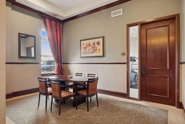 dining space featuring light tile patterned flooring, visible vents, and a wainscoted wall