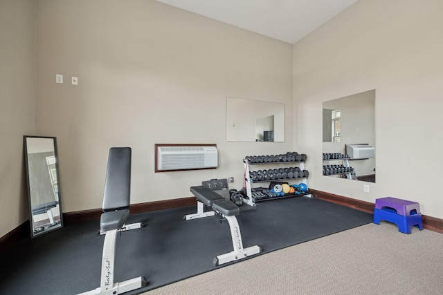 workout room featuring a wall mounted air conditioner, baseboards, and a towering ceiling