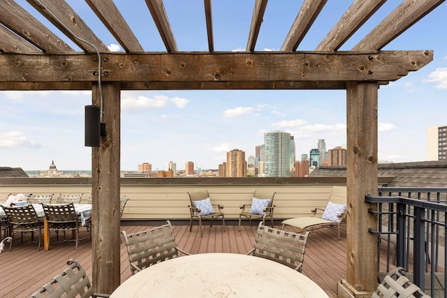 wooden terrace with a city view, outdoor dining area, and a pergola