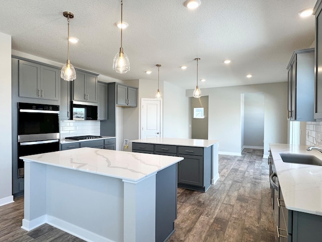 kitchen with a sink, gray cabinetry, dark wood-style floors, and a center island