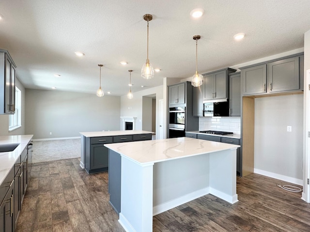 kitchen featuring gray cabinetry, backsplash, a kitchen island, gas stovetop, and black microwave