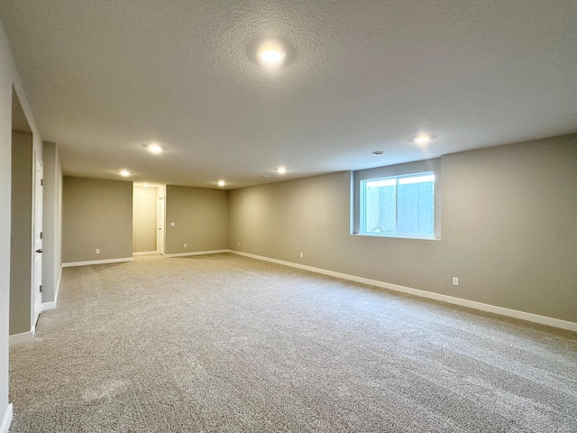 basement with light carpet, recessed lighting, a textured ceiling, and baseboards