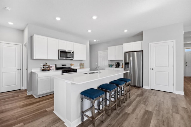 kitchen featuring a sink, light wood-style floors, a kitchen island with sink, and stainless steel appliances