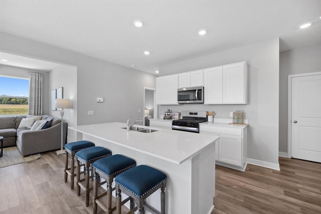 kitchen featuring a breakfast bar, wood finished floors, stainless steel appliances, and a sink