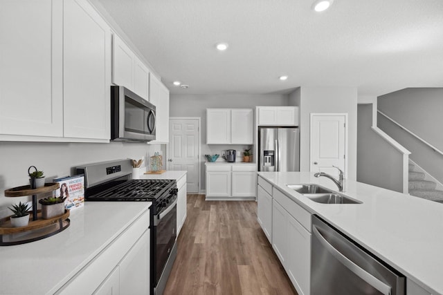 kitchen featuring light countertops, recessed lighting, appliances with stainless steel finishes, white cabinets, and a sink