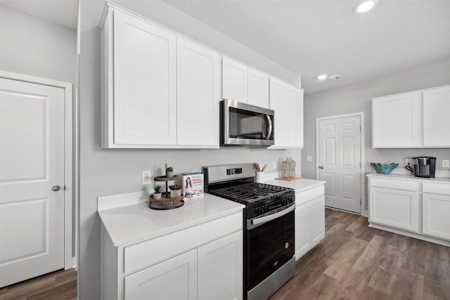 kitchen featuring stainless steel appliances, dark wood-type flooring, white cabinets, and light countertops