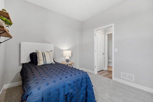 carpeted bedroom with radiator heating unit, baseboards, visible vents, and connected bathroom