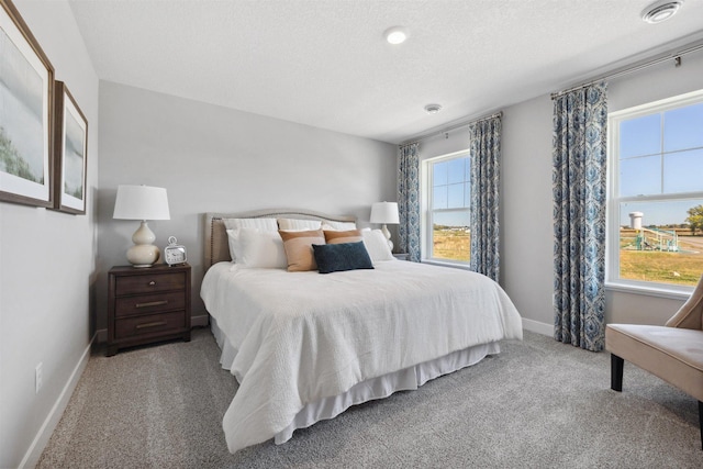 carpeted bedroom with a textured ceiling and baseboards