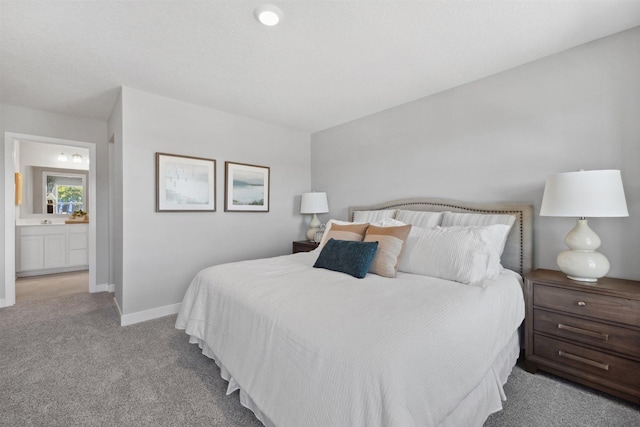 bedroom with baseboards, carpet floors, and ensuite bath