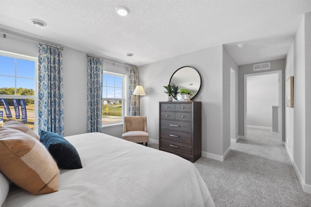 bedroom featuring a textured ceiling, carpet, visible vents, and baseboards