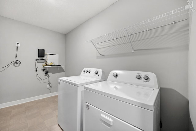 washroom featuring laundry area, washing machine and dryer, light floors, and baseboards