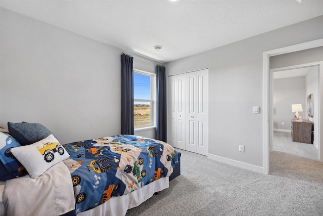 bedroom featuring a closet, baseboards, carpet, and a textured ceiling