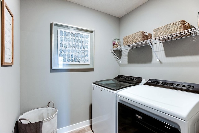 laundry area with laundry area, baseboards, independent washer and dryer, and light wood-type flooring