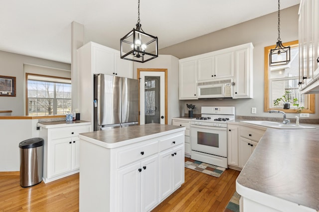 2316 Coldwater Xing, Mayer, MN 55360 - kitchen featuring white appliances, a sink, light wood finished floors, a center island, and a chandelier