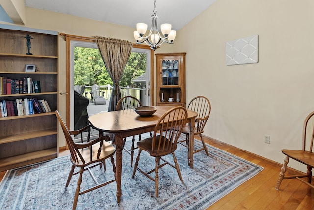 dining area featuring a notable chandelier, lofted ceiling, and wood finished floors