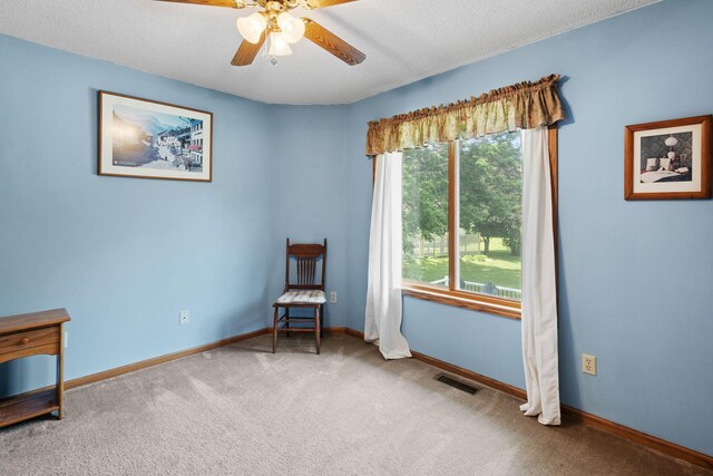 unfurnished room featuring visible vents, a textured ceiling, carpet floors, baseboards, and ceiling fan